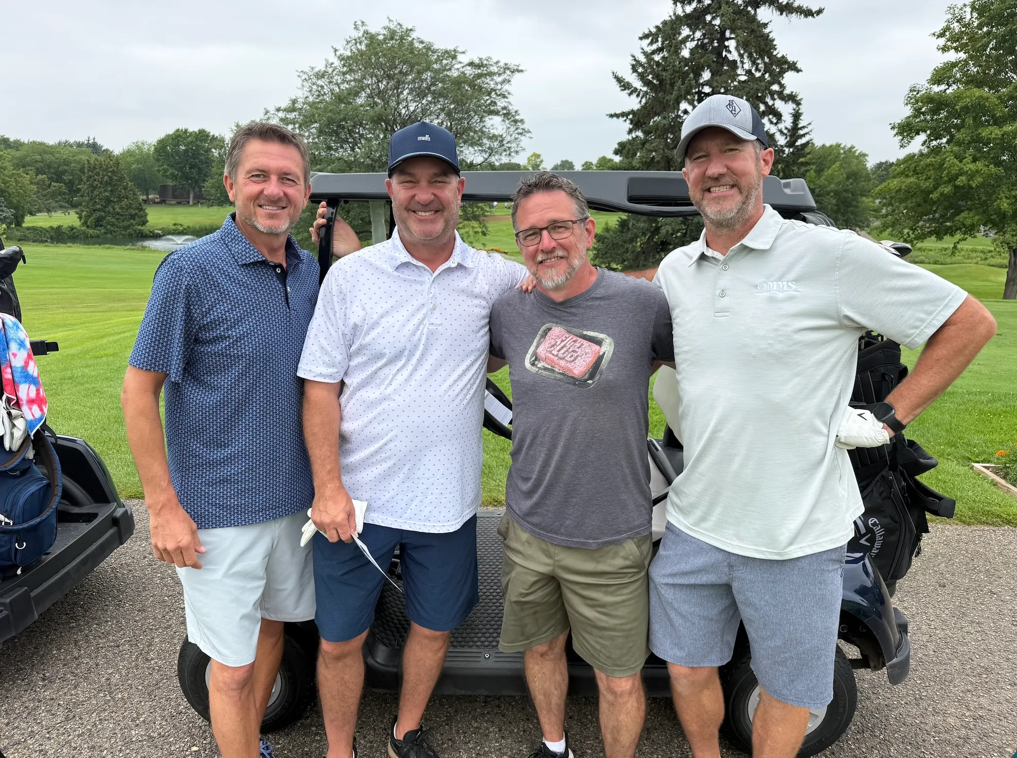 Golfers gathered by a golf cart