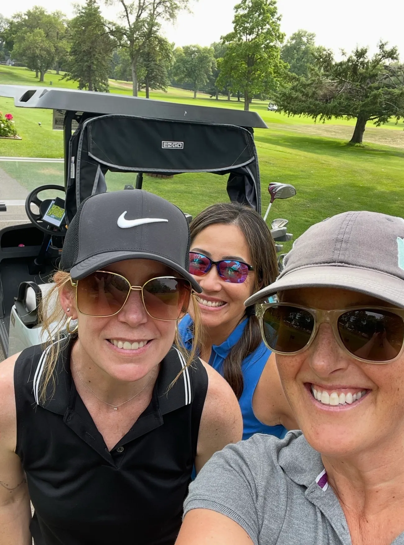 Three golfers taking a selfie by a golf cart
